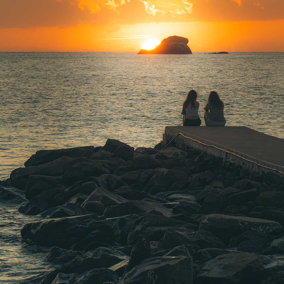 Two friends watching the sunset together at BodyHoliday St Lucia